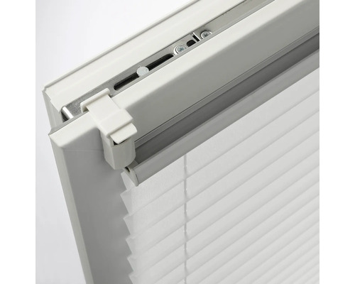 Vue détaillée d'un store plissé blanc avec support de serrage Klemmfix pour un montage sans perçage sur le cadre de la fenêtre.