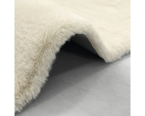 Hochflor-Kunstfell-Teppich in Creme, weiche Textur mit sichtbarer dunkler Rückseite.