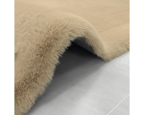 Beigefarbener, weicher Kunstfellteppich mit Hochflor und strukturierter Rückseite.