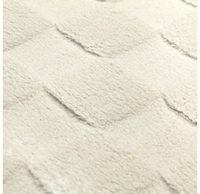 Detailaufnahme der weichen Oberflächenstruktur eines Teppichs mit geometrischem Hoch-Tief-Muster.