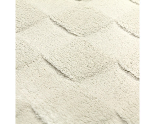 Detailaufnahme der weichen Oberflächenstruktur eines Teppichs mit geometrischem Hoch-Tief-Muster.
