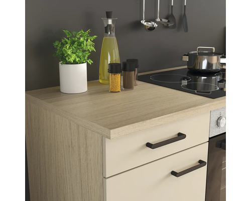 Cuisine moderne avec plan de travail effet bois, façades claires, plaque de cuisson intégrée, four et ustensiles de cuisine bien rangés.