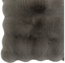 Coussin d'assise doux et moelleux en fausse fourrure avec bord ondulé.