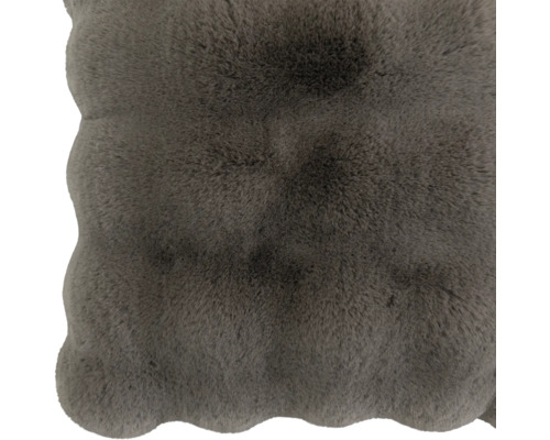 Coussin d'assise doux et moelleux en fausse fourrure avec bord ondulé.