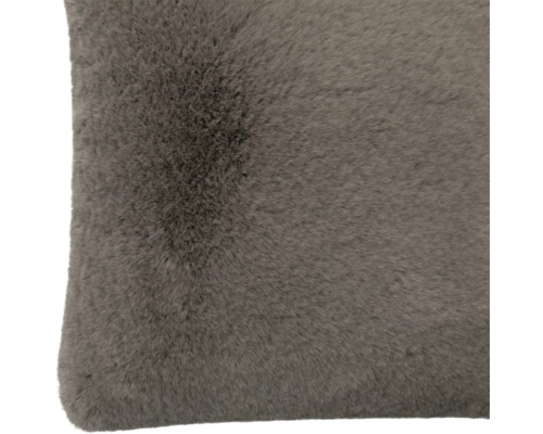 Gros plan d'un coussin décoratif doux en fausse fourrure gris-brun.