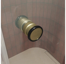 Un raccord de baignoire ou de douche en métal encastré dans le mur avec bague d étanchéité devant un mur carrelé.