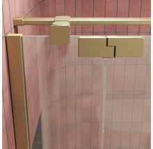 Paroi de douche en verre avec profilé doré mat et raccord mural dans une cabine de douche carrelée