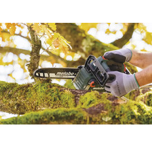 Eine Person benutzt eine akkubetriebene Metabo Kettensäge zum Schneiden eines moosbewachsenen Astes in einem herbstlichen Garten.