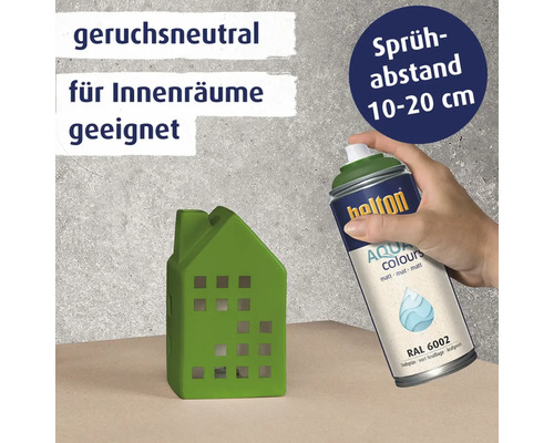 Eine Hand sprüht mit einer Belton Aqua Colours Sprühdose auf ein grünes Deko Haus aus Keramik.