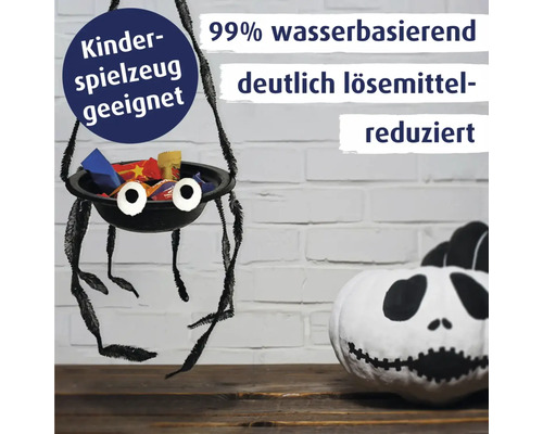 Halloween Dekoration mit einer hängenden Spinnen Schale voller Süßigkeiten und einem bemalten Kürbis vor einer Backsteinwand