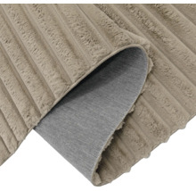 Ein Teppich mit weicher Struktur und geripptem Design, dessen Ecke umgeschlagen ist und die Rückseite zeigt.