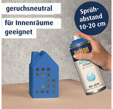 Eine Hand hält eine Belton Aqua Sprühdose und lackiert ein kleines Hausmodell in Enzianblau.