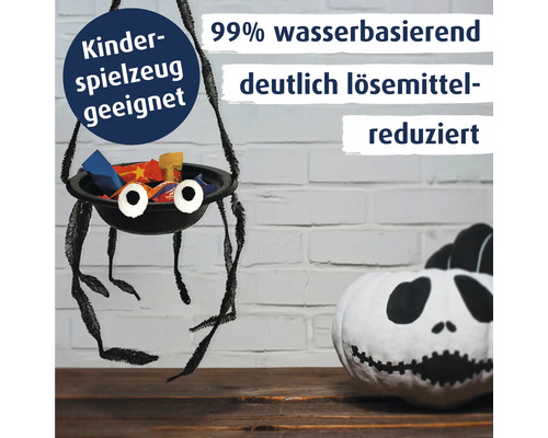 Eine handgebastelte Spinnen-Süßigkeitenschale aus Farbe und Pfeifenreinigern neben einem bemalten Kürbis als Halloween Dekoration.