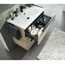 Waschtischunterschrank in Holzoptik mit weissem Waschbecken und ausgezogener Schublade inklusive Ordnungssystem und Handtuchhalter im Badezimmer.