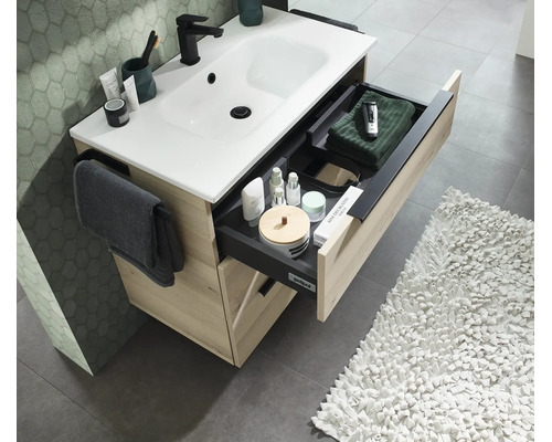 Waschtischunterschrank in Holzoptik mit weissem Waschbecken und ausgezogener Schublade inklusive Ordnungssystem und Handtuchhalter im Badezimmer.