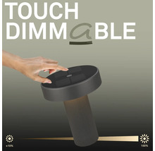Eine Hand bedient die Touch Dimmfunktion an einer modernen LED Tischleuchte mit geripptem Fuss und flachem Leuchtenkopf.
