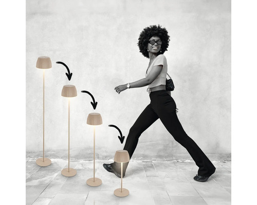 Une femme marche à côté de quatre lampadaires réglables en hauteur avec abat-jour nervuré, présentés par paliers de hauteur décroissants.