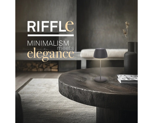 Moderne Tischleuchte im minimalistischen Design auf einem runden Holztisch in einem elegant eingerichteten Wohnzimmer.