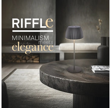 Moderne Tischleuchte im minimalistischen Design auf einem runden Holztisch in einem elegant eingerichteten Wohnzimmer.