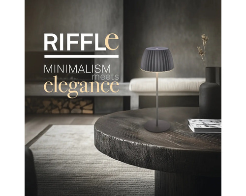 Moderne Tischleuchte im minimalistischen Design auf einem runden Holztisch in einem elegant eingerichteten Wohnzimmer.