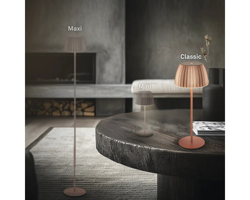 Drei verschiedene Grössen der LED Tisch und Stehleuchte mit plissiertem Schirm in einem modern eingerichteten Wohnzimmer mit Kamin.