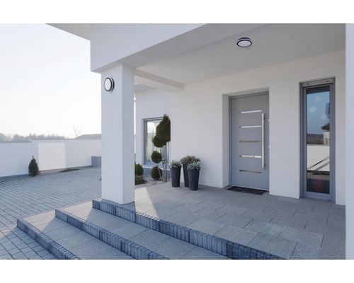 Eingangsbereich eines modernen Hauses mit grauer Tür, Treppe und Aussenbeleuchtung