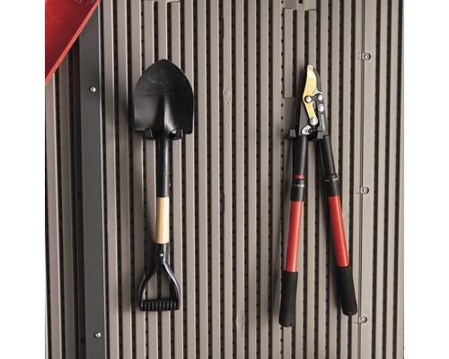 Une bêche et un ébrancheur sont accrochés au mur.