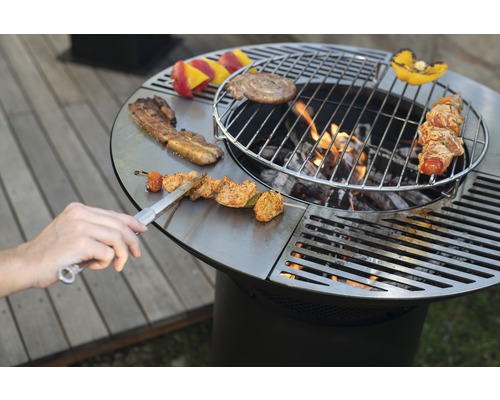 Barbecue rond avec aliments et ustensiles de grillade sur la surface de cuisson