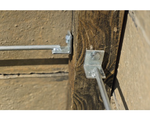 Detailansicht von einem Holzpfosten mit einem daran befestigten Drahtseilhalter.