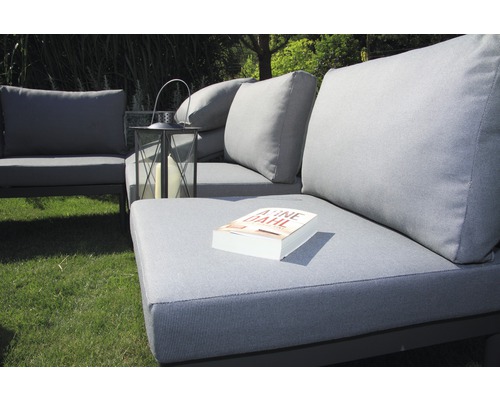 Gartensitzgruppe mit grauen Polstern und einer Laterne auf einer Rasenfläche