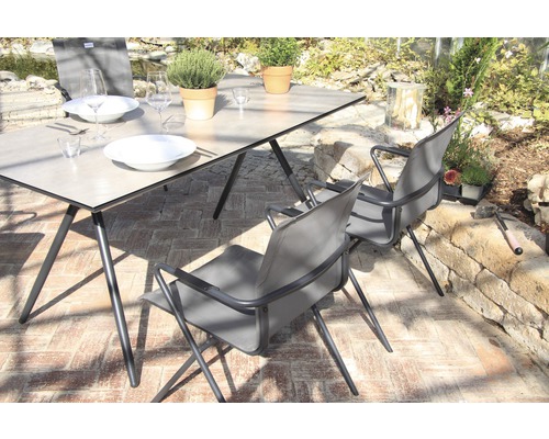 Scène avec table à manger et chaises pour l''extérieur, dressée avec de la vaisselle et des plantes.
