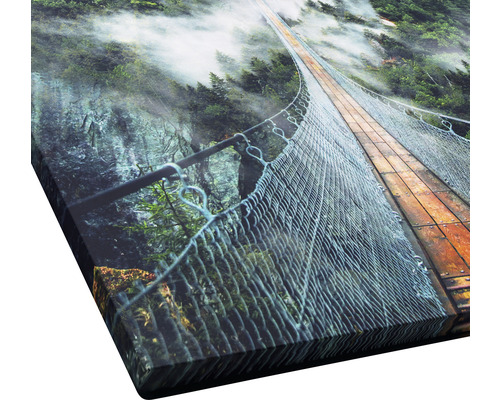 Gros plan d''une reproduction artistique représentant un pont suspendu au-dessus d''un canyon boisé