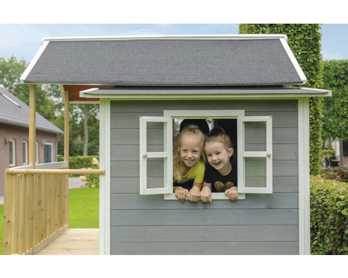 Zwei Kinder schauen aus dem Fenster eines Spielhauses aus Holz.