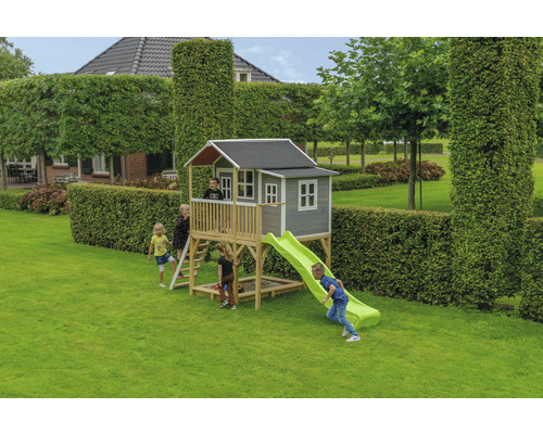 Spielhaus mit Rutsche und Sandkasten im Garten mit spielenden Kindern