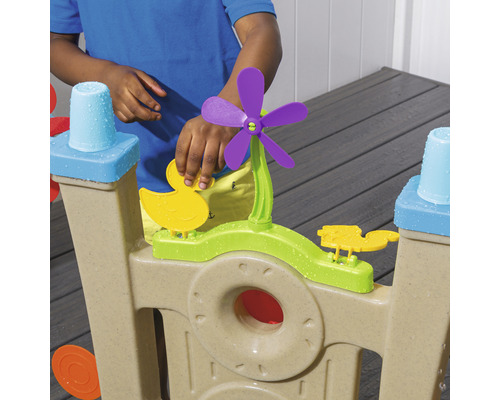 Enfant jouant avec un circuit d''eau avec des canards et une éolienne.