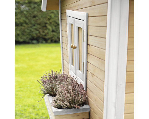 Detailansicht eines Holzspielhauses mit Fenster, Fensterbank und Bepflanzung