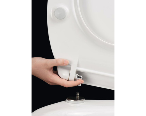 Une main installe un siège de toilette sur une toilette.