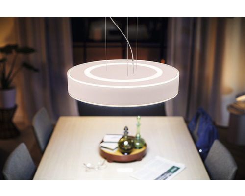 Abat-jour rond en tissu éclairé au-dessus d''une table de salle à manger.