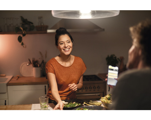 Cuisine lumineuse avec une femme souriante et une personne avec un smartphone