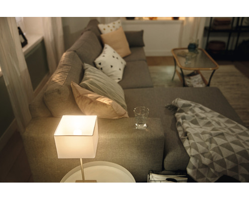 Salon avec canapé d''angle gris, coussins, lampe de table et table d''appoint