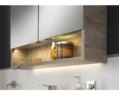 Armoire de toilette avec compartiment de rangement ouvert et éclairage dans la salle de bain