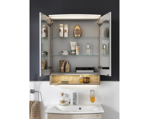 Armoire de toilette ouverte avec éclairage et produits de bain au-dessus d''un lavabo