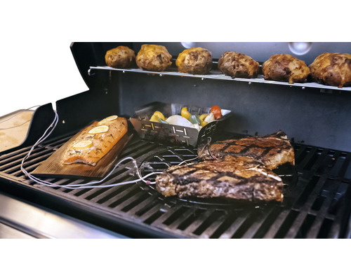 Sur un gril, il y a des steaks, des pommes de terre, des légumes et du saumon sur une planche en bois.