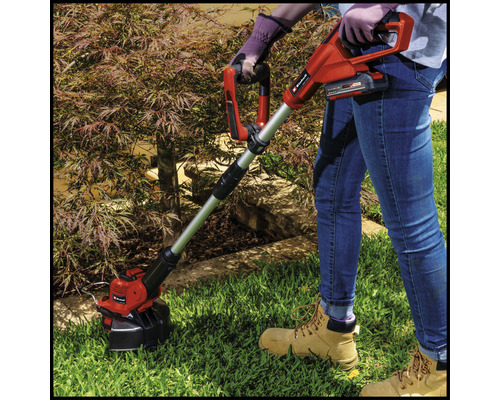 Une personne utilise un coupe-bordure sans fil dans le jardin.