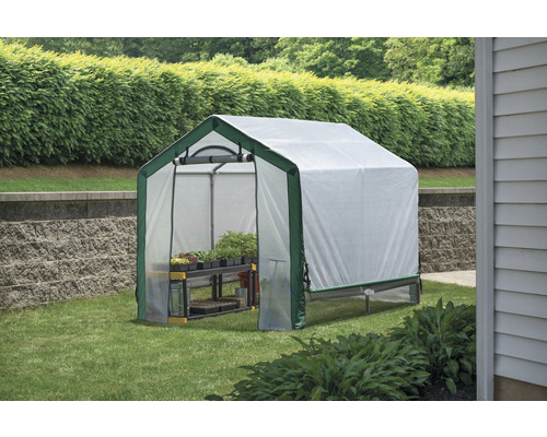 Serre avec étagères dans le jardin