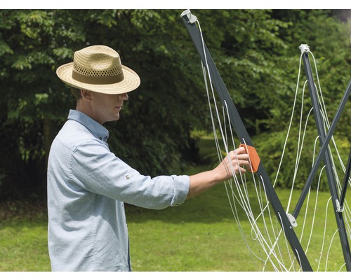Homme installant un séchoir à linge rotatif dans le jardin.