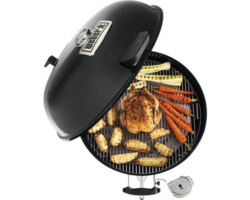 Kugelgrill mit Grillgut wie Hähnchen, Kartoffeln und Gemüse