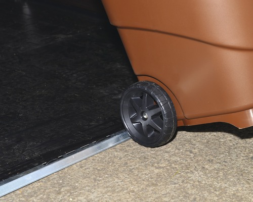 Detailansicht einer braunen Mülltonne mit einem schwarzen Rad