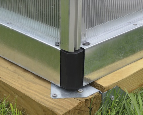 Vue détaillée d''une construction de serre avec des éléments métalliques, des raccords en plastique et des fondations en bois