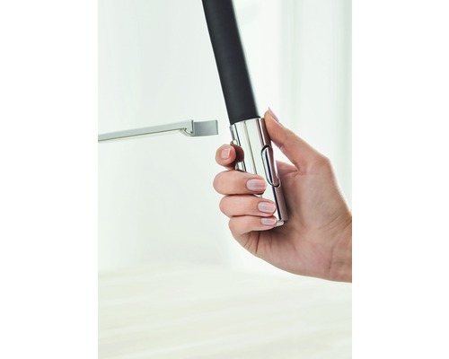 Une main tient une barre de douche réglable en métal